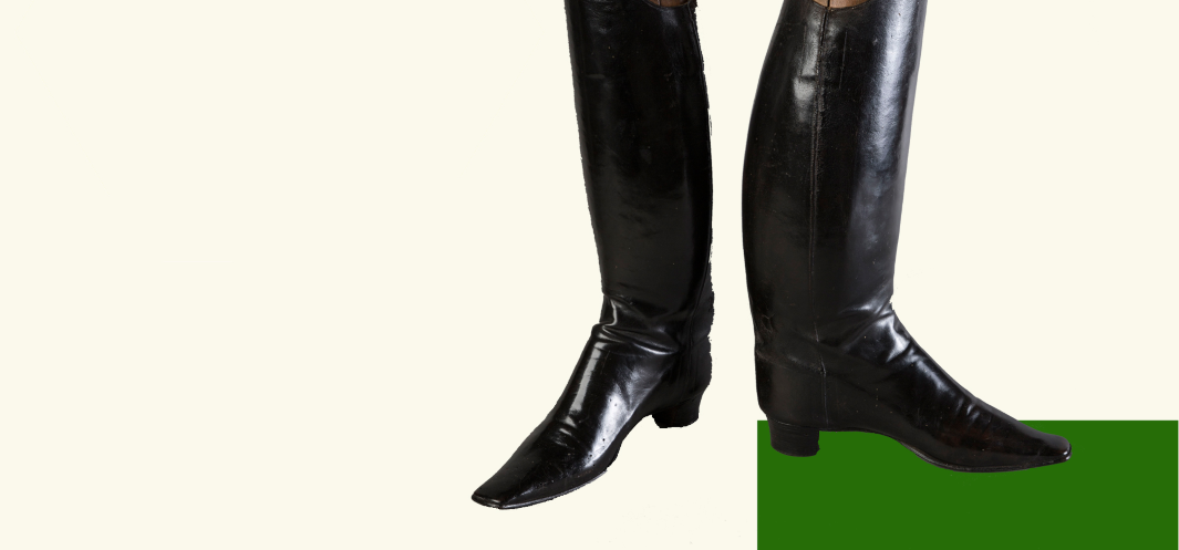 Kolaż przedstawia parę czarnych, skórzanych butów z wysoką cholewką i niewielkim obcasem. Buty następują na zielony czworokąt umieszczony na białym tle.