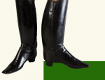 Kolaż przedstawia parę czarnych, skórzanych butów z wysoką cholewką i niewielkim obcasem. Buty następują na zielony czworokąt umieszczony na białym tle.