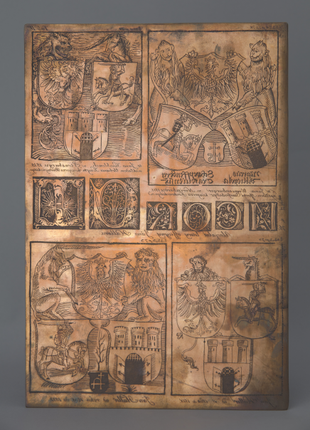 Grafika złożona z czterech paneli, w których umieszczono herby z orłami, rycerzami na koniach, twierdzami. Herby są trzymane przez mityczne postaci, między innymi gargulce i jednorożce.