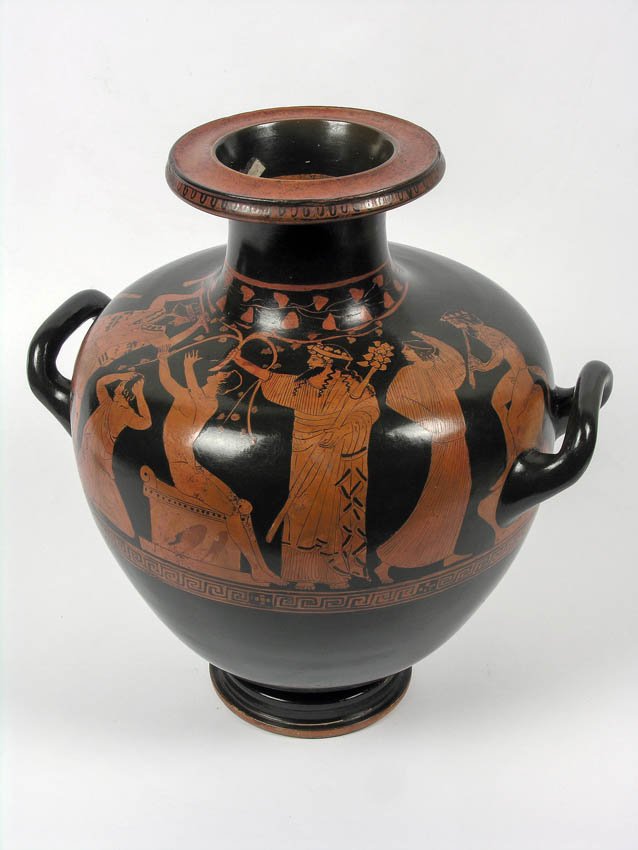 Czarny ceramiczny dzban o kulistym korpusie i szerokiej szyi z dwiema uszami, ozdobiony czerwono‑pomarańczowym pasem figuralnym z kilkoma stojącymi postaciami w długich strojach, jedną postacią siedzącą przy niskim stołku oraz zwierzęciem przypominającym psa, z geometrycznym ornamentem u dołu i dekoracyjnym wzorem przy szyi.