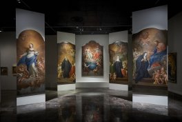 Galeria z pięcioma wysokimi, łukowatymi obrazami ustawionymi w półokręgu, każdy przedstawia figuratywne sceny religijne z postaciami w bogatych szatach i aniołkami, centralny panel jest jaśniejszy, sufit ciemny, a błyszcząca podłoga odbija obrazy.