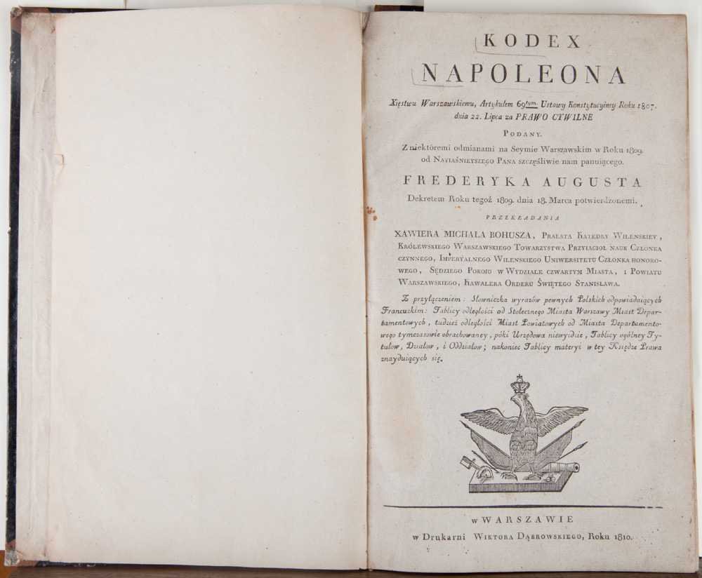 Otwarta stara książka na jasnym tle; lewa strona pusta, prawa to tytułowa kartka z dużym nagłówkiem "KODEX NAPOLEONA", drukowanym tekstem po polsku (m.in. fragment "FREDERYKA AUGUSTA"), datą "Roku 1810" u dołu oraz ryciną orła z koroną i symbolami, z widocznymi przebarwieniami, plamkami i postrzępionymi krawędziami.