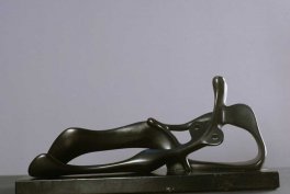 Gładka ciemna metalowa abstrakcyjna rzeźba o wydłużonych, płynnych kształtach przypominająca leżącą sylwetkę, ustawiona na prostokątnej podstawie na jasnym neutralnym tle.