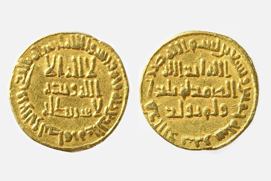Dwa złote okrągłe numizmity ustawione obok siebie na jasnym tle, każda z wypukłymi arabskimi napisami w centralnej części i pierścieniem legendy wokół, z lekko nieregularnymi krawędziami.
