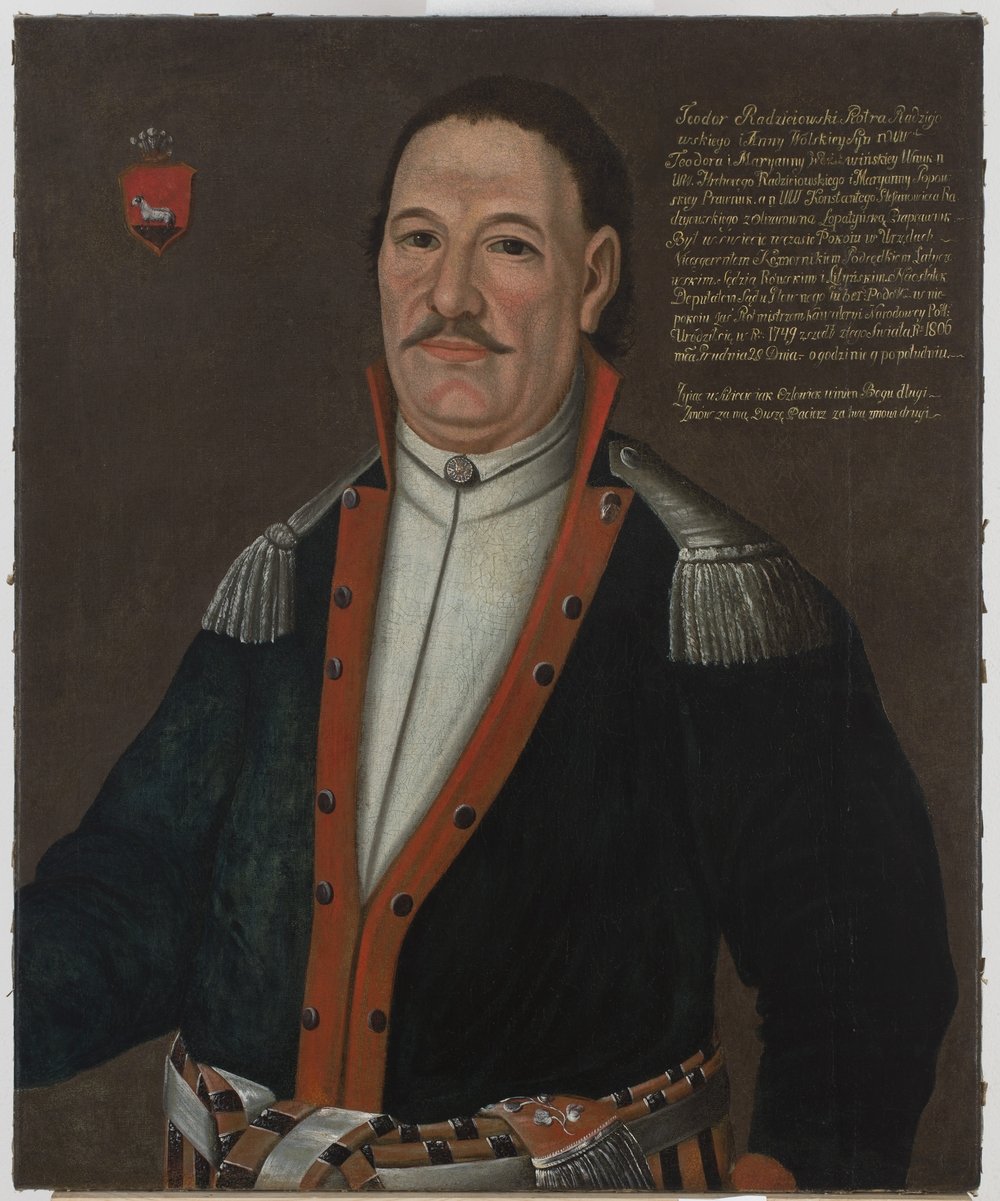 Portret malarski półpostać mężczyzny z krótkimi ciemnymi włosami i wąsem, ubrany w ciemny płaszcz z czerwonym obszyciem i srebrnymi naramiennikami, biała koszula z wysokim kołnierzem i ozdobny pas u bioder, na brązowym tle w lewym górnym rogu herb tarczy, w prawym górnym rogu złota inskrypcja.