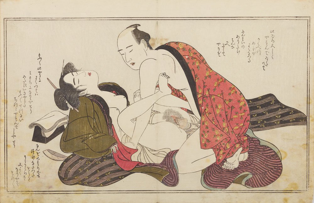 Japońska grafika ukiyo-e na kremowym tle z cienką ramką przedstawiająca parę w intymnej scenie erotycznej — kobieta z upiętymi włosami i ozdobną szpilką leży na poduszkach i tkaninach, mężczyzna w częściowo odkrytym czerwonym, wzorzystym kimonie klęczy nad nią, a w tle widoczne są pionowe fragmenty japońskiego pisma.