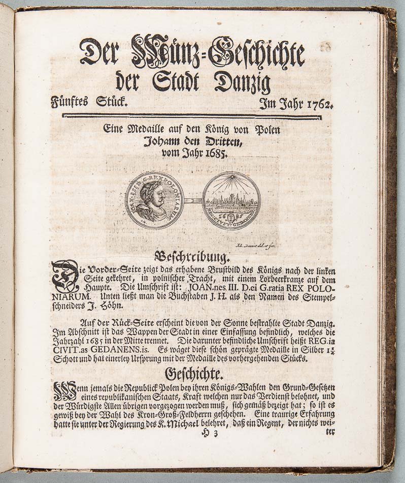 Strona z zabytkowej książki na pożółkłym papierze z tytułem w gotyckiej czcionce u góry (między innymi widoczny napis „Der Münz-Geschichte der Stadt Danzig” i data „Im Jahr 1762”), poziomą kreską oddzielającą nagłówek, dwoma okrągłymi rycinami medali pośrodku (jedna z profilowym popiersiem, druga z panoramą zabudowań), oraz kilkoma akapitami niemieckiego tekstu drukowanego poniżej z dużą zdobioną inicjałą rozpoczynającą jeden z paragrafów.