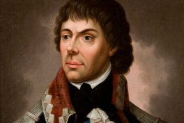 Portret malarski przedstawiający mężczyznę z ciemnymi, lekko kręconymi włosami i jasną cerą, ubrany w jasny płaszcz z geometrycznym wzorem na kołnierzu, bordowy szal, białą koszulę z fałdowaną kryzą i czarną kokardą, na rozmytym ciemnym tle.
