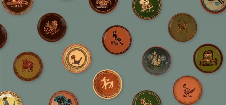 Kilka okrągłych ceramicznych talerzy w różnych kolorach rozmieszczonych na zielonoszarym tle, każdy z prostym, stylizowanym motywem zwierzęcym (ptaki, królik, jeleń, kaczka) i dekoracyjną obwódką.