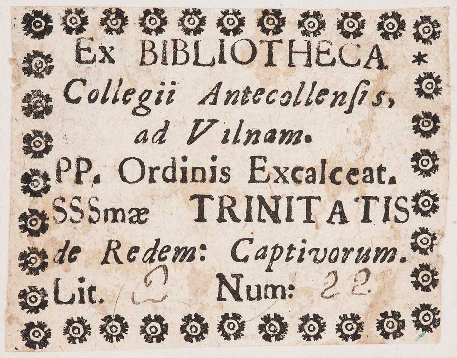 Etykieta biblioteczna na pożółkłym papierze z dekoracyjną ramką z drobnych rozetek oraz kilkoma liniami czarnego, częściowo odręcznego tekstu łacińskiego, widoczne m.in. słowa Ex BIBLIOTHECA, TRINITATIS i oznaczenie Num: 22.