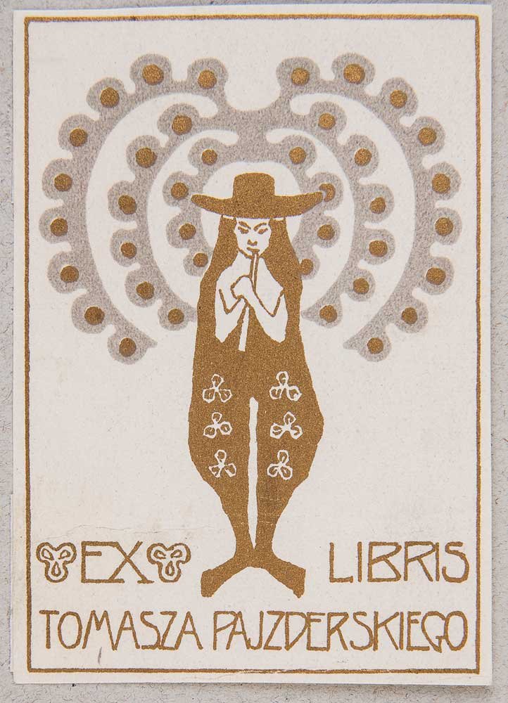Ekslibris w brązowo-szarych tonach z sylwetką osoby w szerokim kapeluszu trzymającej flet przed ustami, długim ozdobnym płaszczem z motywami, spiralnym ornamentem z kropkami w tle oraz napisem EX LIBRIS TOMASZA PAJZDERSKIEGO.
