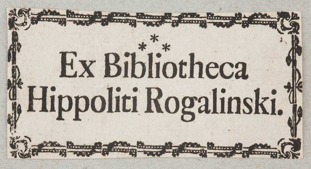 Prostokątna kremowa etykieta z ozdobną czarną bordiurą i dużym drukowanym napisem Ex Bibliotheca Hippoliti Rogalinski z trzema gwiazdkami umieszczonymi nad napisem.