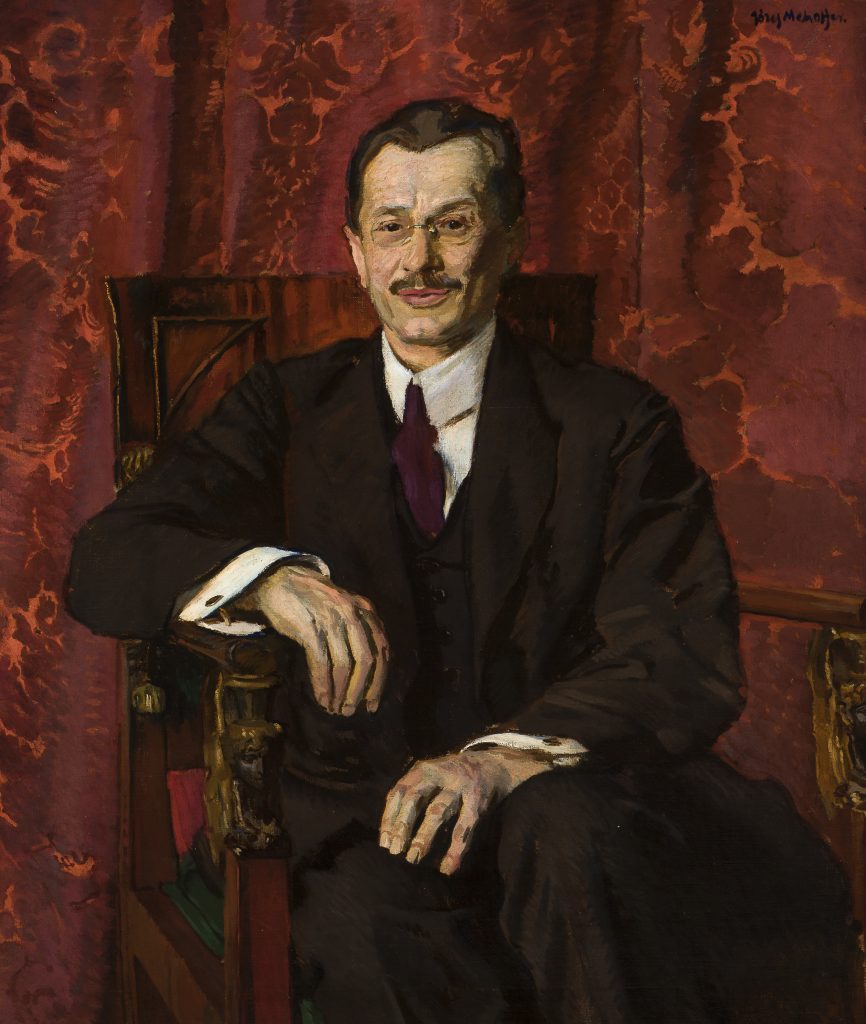 Portret siedzącego mężczyzny do połowy ciała w ciemnym garniturze, białej koszuli i ciemnym krawacie, z wąsami i okularami, z jedną ręką spoczywającą na zdobionym, drewnianym podłokietniku, na tle czerwonych, ornamentowanych zasłon, z podpisem w prawym górnym rogu.